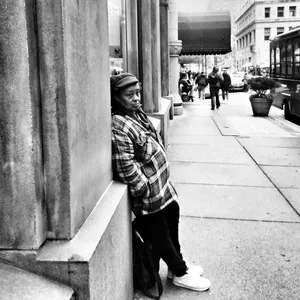 Woman relaxes against a building on Wood St waiting for the PAT bus.